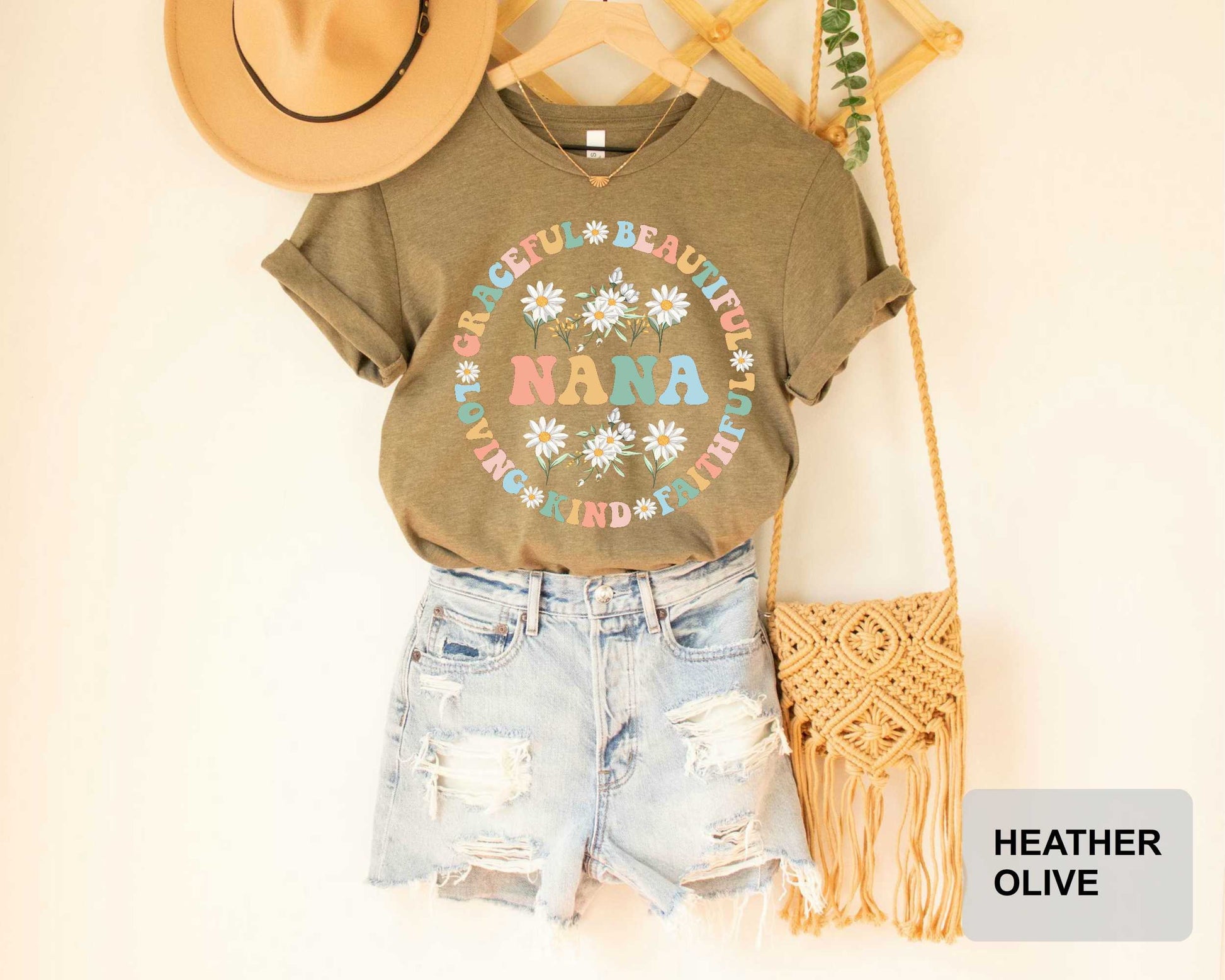 A casual outfit consisting of a t-shirt with a floral design, distressed denim shorts, and a straw boa is displayed on a hanger.